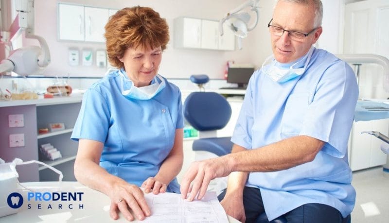 Two dental professionals looking at paperwork.